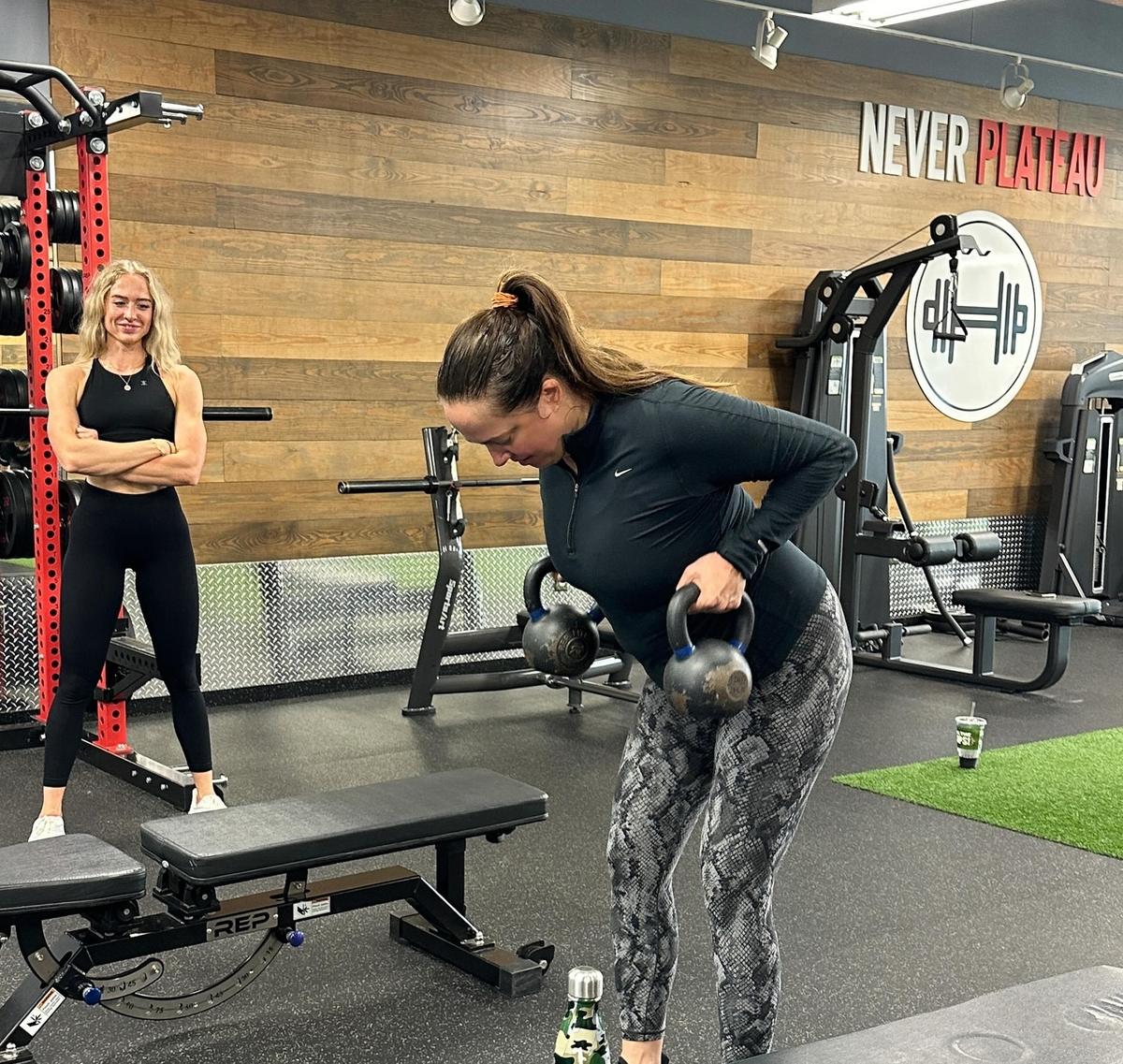 Personal trainer coaching a client through kettlebell rows in the strength area